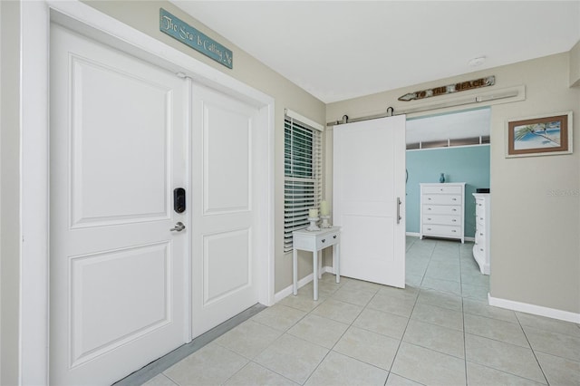 unfurnished bedroom with a barn door, light tile patterned flooring, and baseboards