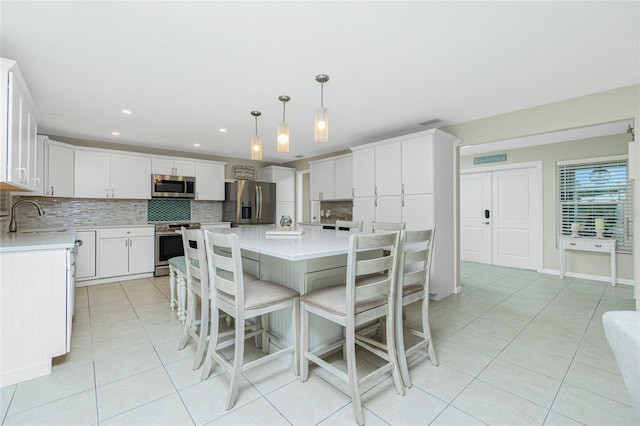 kitchen with light tile patterned flooring, stainless steel appliances, a sink, light countertops, and backsplash