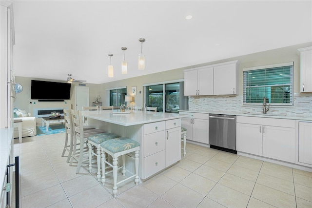 kitchen with decorative backsplash, open floor plan, a sink, dishwasher, and a kitchen bar