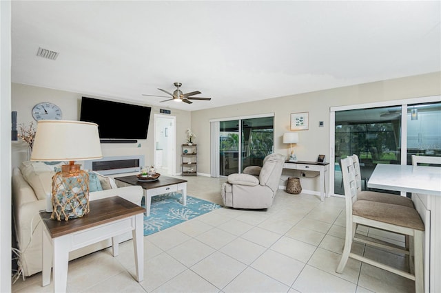 living room featuring baseboards, light tile patterned flooring, visible vents, and a ceiling fan