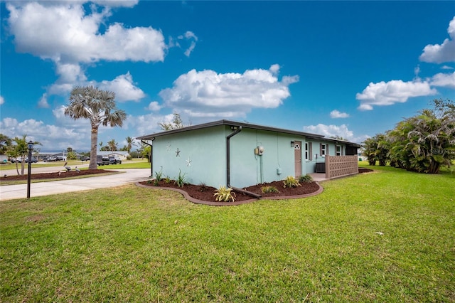 view of property exterior with a lawn, driveway, and stucco siding