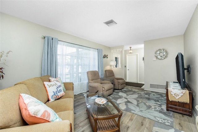 living area featuring visible vents and wood finished floors