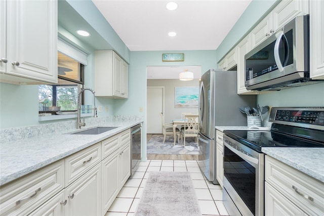 kitchen featuring light tile patterned floors, stainless steel appliances, recessed lighting, white cabinets, and a sink