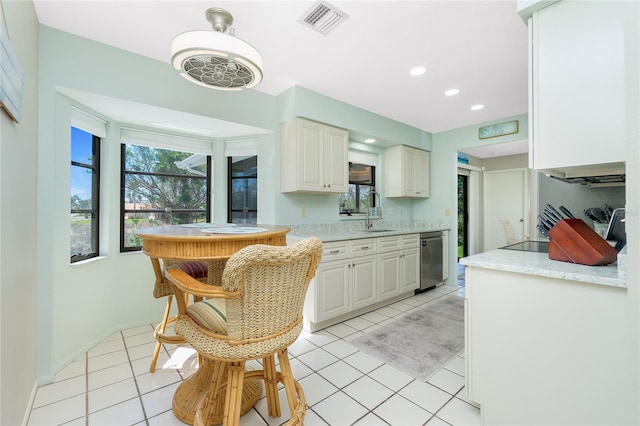 kitchen with visible vents, white cabinets, stainless steel dishwasher, a sink, and light tile patterned flooring