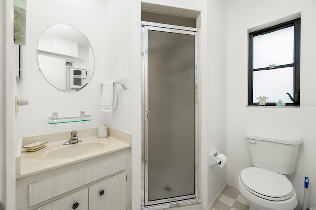 bathroom with vanity, a shower stall, toilet, and baseboards