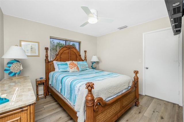 bedroom with light wood-style floors, visible vents, and a ceiling fan