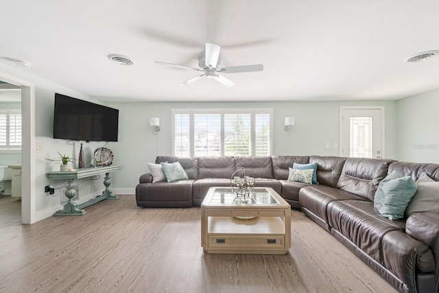 living room featuring a ceiling fan, visible vents, light wood-style flooring, and baseboards