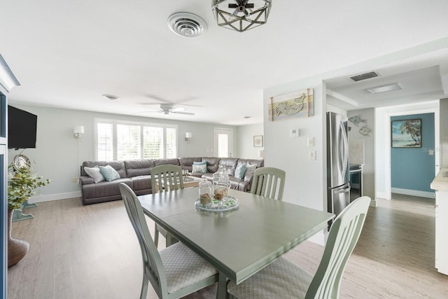 dining space with light wood-type flooring, ceiling fan, visible vents, and baseboards