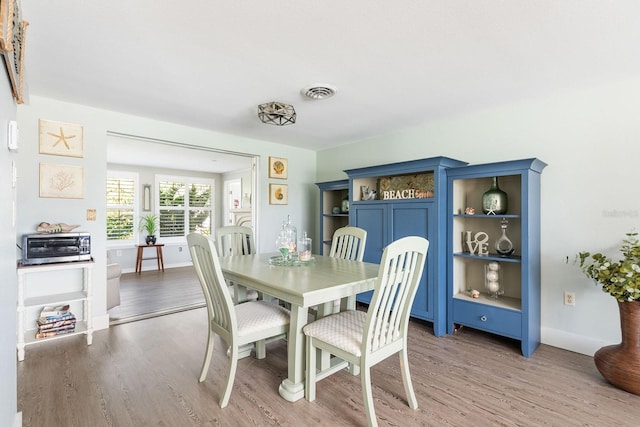 dining room featuring a toaster, light wood-style floors, baseboards, and visible vents