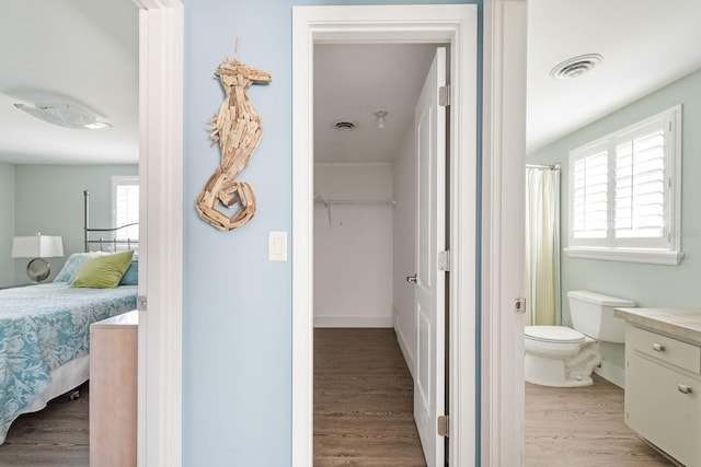 bathroom featuring toilet, ensuite bath, visible vents, and wood finished floors