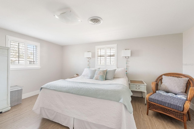 bedroom featuring visible vents, light wood-style flooring, and baseboards