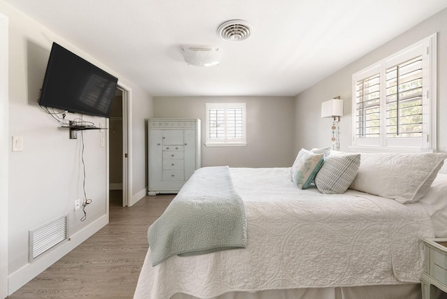 bedroom featuring visible vents, baseboards, and wood finished floors