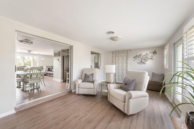 living area with visible vents, baseboards, and wood finished floors