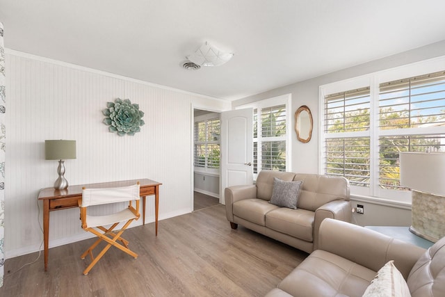 living area with wood finished floors, visible vents, and baseboards