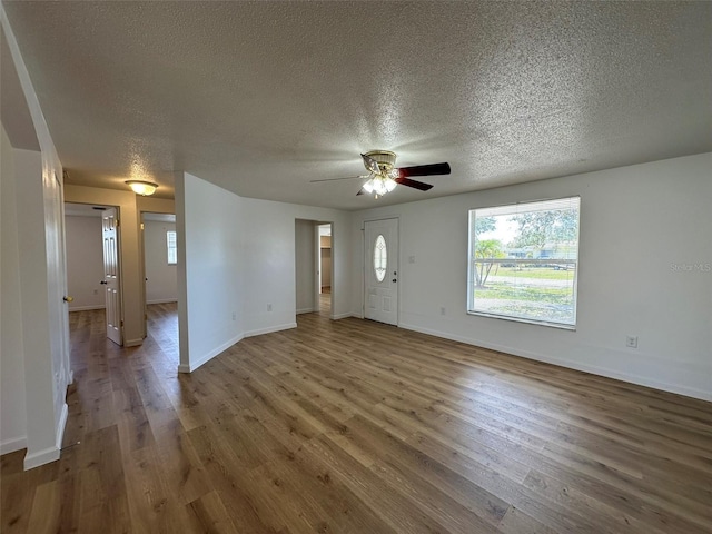 192 Garden Ave NW, Port Charlotte, FL 33952 - unfurnished living room with ceiling fan, a textured ceiling, baseboards, and wood finished floors