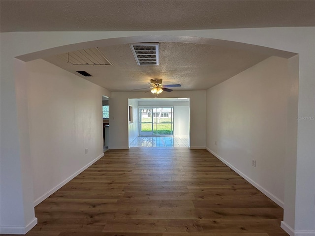 192 Garden Ave NW, Port Charlotte, FL 33952 - spare room with a textured ceiling, visible vents, arched walkways, and wood finished floors