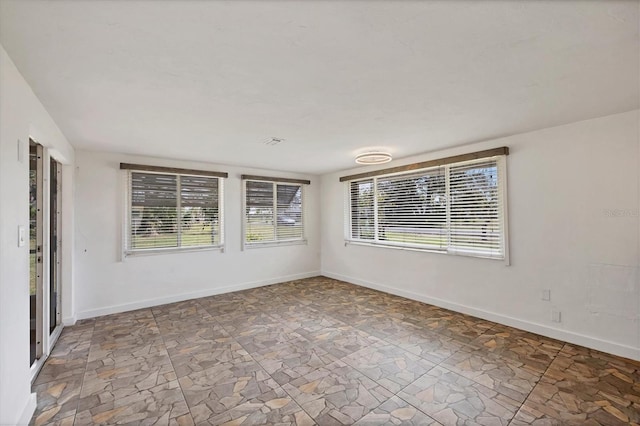 empty room featuring stone finish floor and baseboards