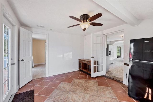 interior space featuring ceiling fan, beamed ceiling, tile patterned floors, and baseboards