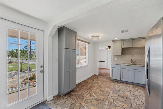 kitchen with freestanding refrigerator, a sink, and gray cabinetry