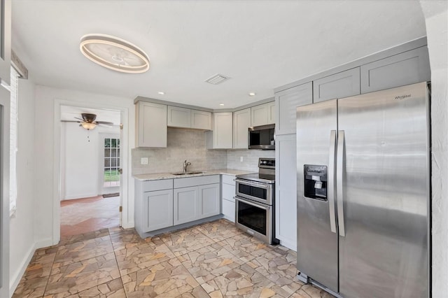 840 E 7th St, Englewood, FL 34223 - kitchen with stainless steel appliances, gray cabinetry, decorative backsplash, recessed lighting, and a ceiling fan