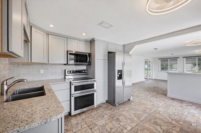 840 E 7th St, Englewood, FL 34223 - kitchen featuring stainless steel appliances, gray cabinetry, decorative backsplash, light stone counters, and recessed lighting