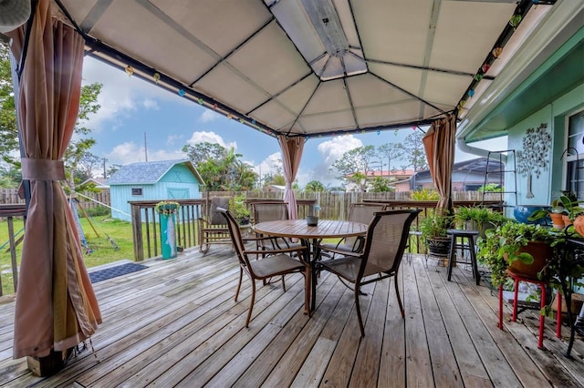 deck featuring an outbuilding, outdoor dining area, a fenced backyard, a yard, and a storage unit