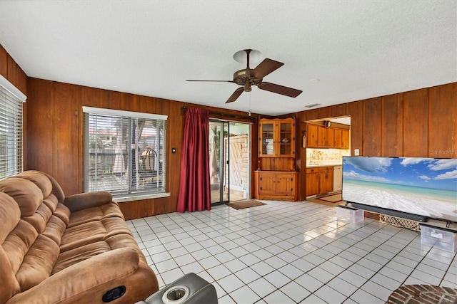 unfurnished living room featuring wood walls, a wealth of natural light, and light tile patterned flooring