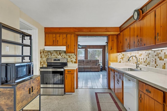 kitchen with under cabinet range hood, appliances with stainless steel finishes, light countertops, and a sink