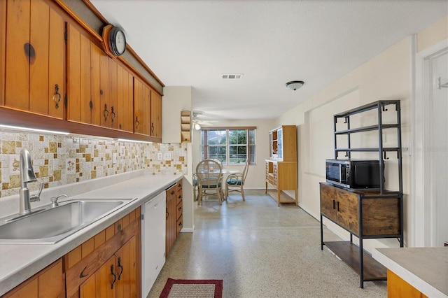 kitchen featuring visible vents, decorative backsplash, brown cabinets, white dishwasher, and a sink