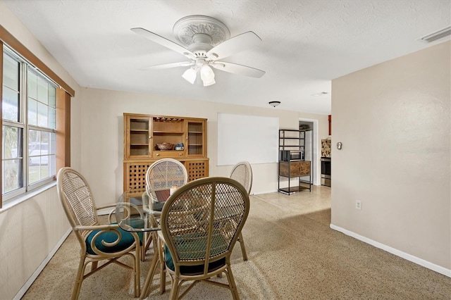 dining area featuring visible vents, a ceiling fan, a textured ceiling, baseboards, and speckled floor