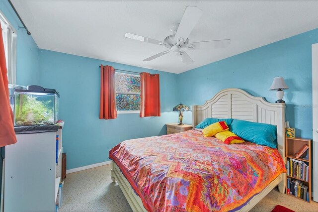 bedroom with ceiling fan, speckled floor, and baseboards