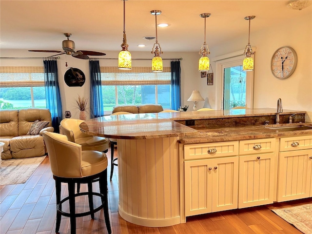 kitchen with stone counters, plenty of natural light, a breakfast bar, and a sink