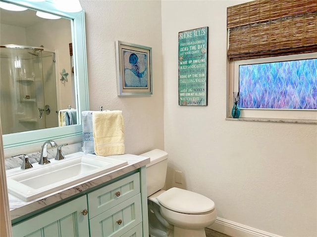 full bathroom with toilet, a stall shower, baseboards, and vanity