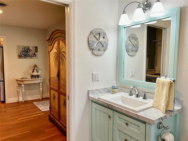 bathroom featuring baseboards, visible vents, wood finished floors, and vanity