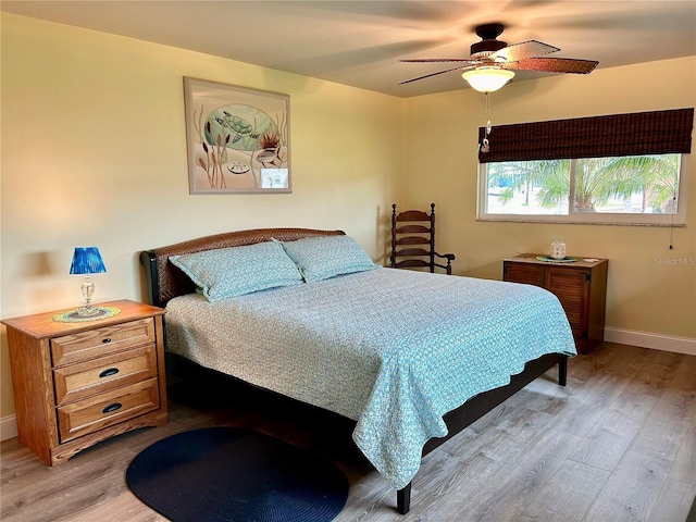 bedroom with light wood finished floors, baseboards, and a ceiling fan