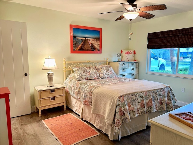 bedroom featuring ceiling fan, baseboards, and wood finished floors