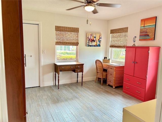 office featuring light wood-style floors, baseboards, a ceiling fan, and a wealth of natural light