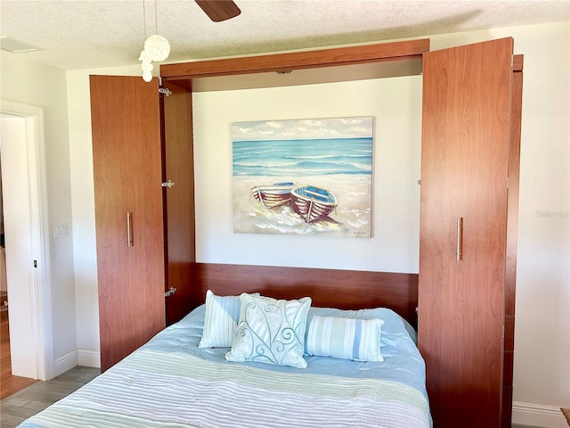 bedroom featuring visible vents, a textured ceiling, baseboards, and wood finished floors