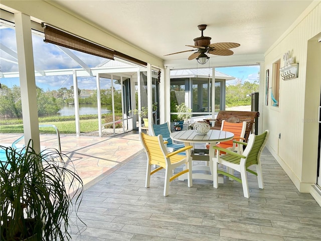 sunroom with a ceiling fan and a water view