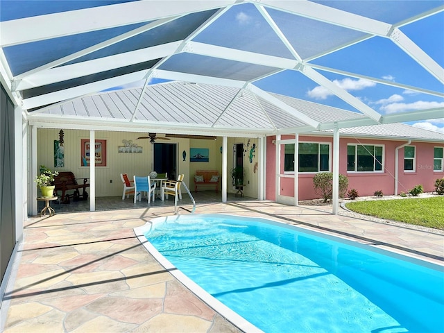 outdoor pool with glass enclosure, a patio area, and a ceiling fan