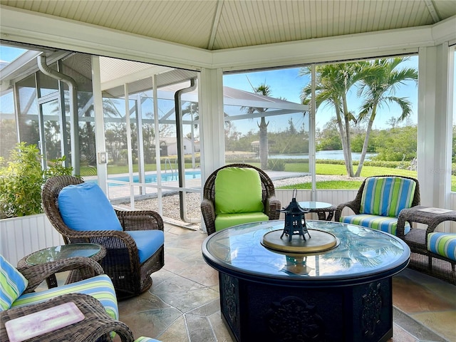 sunroom / solarium featuring vaulted ceiling and a water view