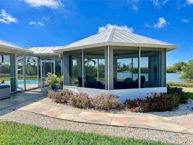 exterior space with a fenced in pool, a standing seam roof, a water view, and metal roof