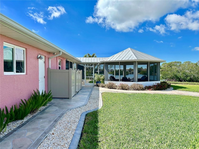 back of property featuring a lawn, a gate, and stucco siding