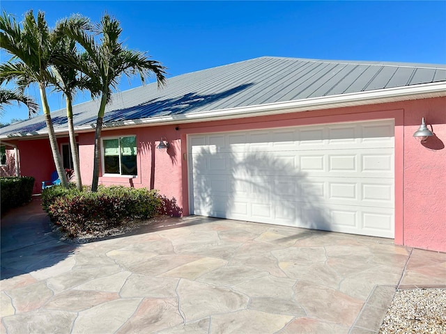 ranch-style home featuring a standing seam roof, metal roof, concrete driveway, and stucco siding