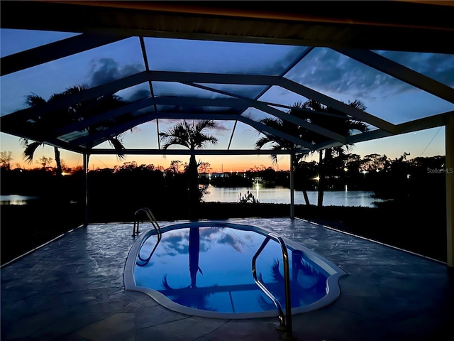 view of swimming pool with a patio area, glass enclosure, and a water view