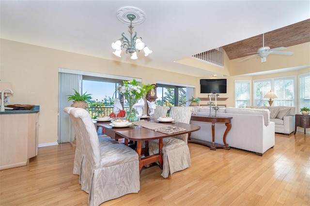 dining space featuring lofted ceiling, ceiling fan with notable chandelier, light wood-type flooring, and baseboards