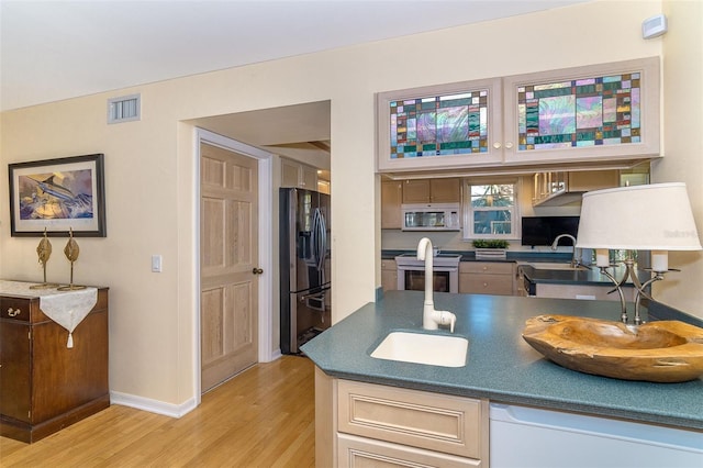 kitchen with visible vents, dark countertops, appliances with stainless steel finishes, light wood-style floors, and a sink