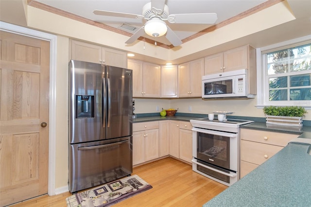 kitchen featuring light brown cabinetry, white appliances, dark countertops, and light wood-style flooring