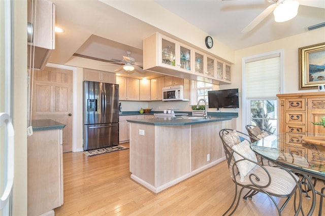 kitchen featuring dark countertops, white microwave, stainless steel fridge, and a peninsula