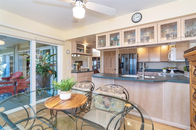 kitchen featuring dark countertops, white microwave, a sink, a peninsula, and stainless steel fridge with ice dispenser